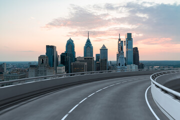 Empty urban asphalt road exterior with city buildings background. New modern highway concrete construction. Concept way to success. Transportation logistic industry fast delivery. Philadelphia. USA.