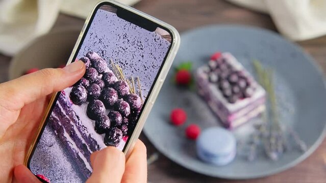 Person recording a video of velvet cake, holding a smartphone, a food blogger, photograph taking photos of delicious dessert served on plate, decorated with fruit and lavender, 4k video clip