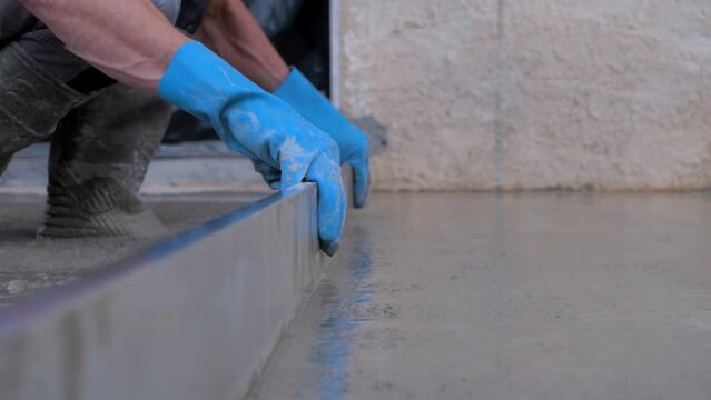 Slowmotion shot of a worker leveling out the freshly poured concrete 