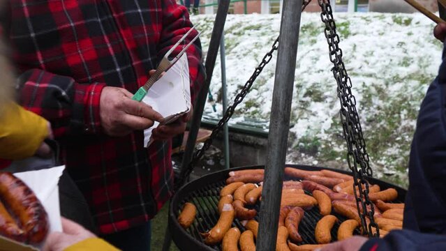 Grilling Polish sausage in winter and putting it on a paper plate