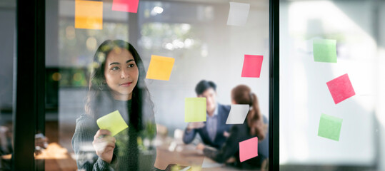 Young confident Businesswoman planning with adhesive notes in creative office. - obrazy, fototapety, plakaty