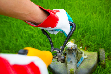 Man trimer mows the grass on the field in the park background