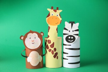 Toy monkey, giraffe and zebra made from toilet paper hubs on green background. Children's handmade ideas