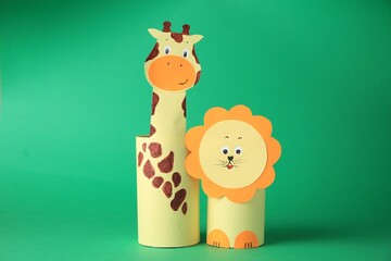 Toy giraffe and lion made from toilet paper hubs on green background. Children's handmade ideas
