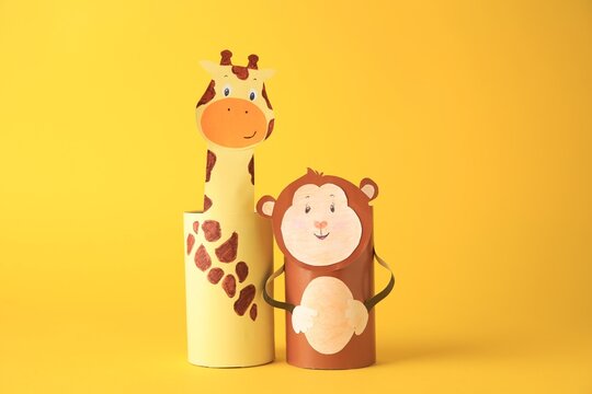 Toy monkey and giraffe made from toilet paper hubs on yellow background. Children's handmade ideas