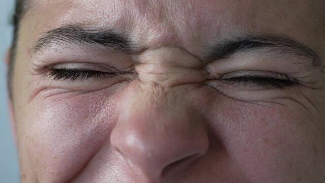 Woman close up face grimacing in macro expression. Female person frowning with happy expression. Wrinkles closeup