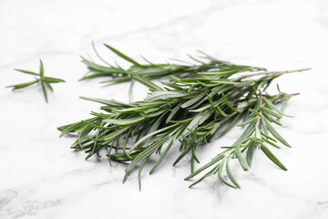 Fototapeta premium Sprigs of rosemary on white marble table, closeup