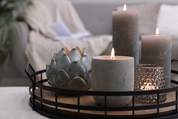 Tray with burning candles on ottoman indoors