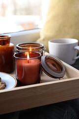Tray with burning candles near window indoors