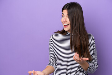 Young Brazilian woman isolated on purple background with surprise expression while looking side