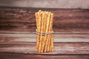 Dry long bread sesame sticks on a brown background