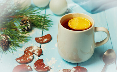 Obraz na płótnie Canvas Christmas still life, a mug of hot tea with lemon on a blue wooden table surrounded by Christmas accessories