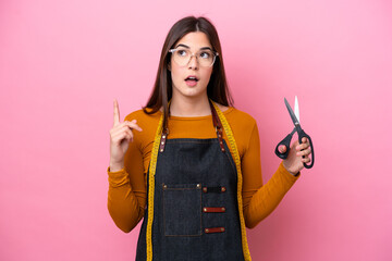 Young Brazilian seamstress woman isolated on pink background thinking an idea pointing the finger up