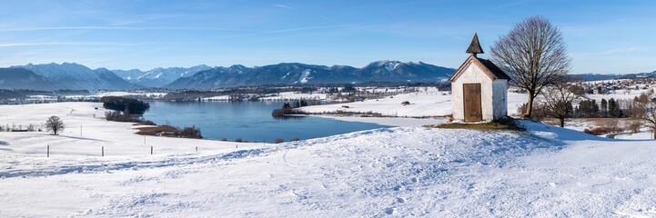Fototapeta na wymiar panoramic view to mountain range behind lake in winter