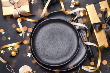 Festive New Year Christmas table with black plate, golden gift box and holiday decorations. top view copy space