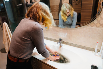 women with plunger and dirty sink with the clog in the pipe.