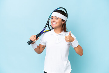 Young tennis player woman isolated on blue background giving a thumbs up gesture