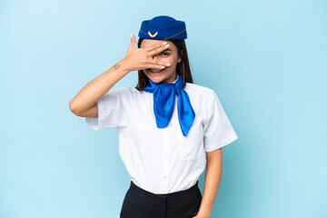 Airplane stewardess caucasian woman isolated on blue background covering eyes by hands and smiling