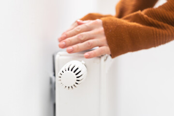 hand adjusting radiator temperature using thermostat. Home with central heating.