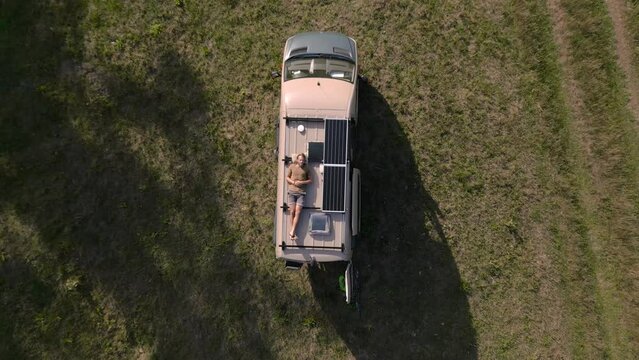 Aerial shot of a man relaxing on the roof of a camper van