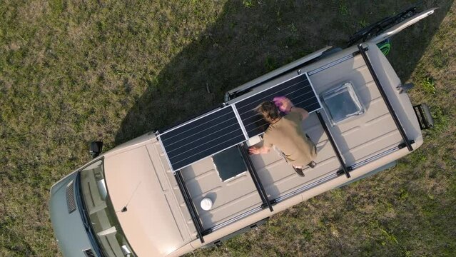 Aerial view of a man cleaning the solar panels on the roof of a caravan
