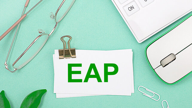 On a light green background there is a white calculator, a computer mouse, green leaves of a plant, gold-rimmed glasses and a white card with text EAP Employee Assistance Program. Business concept