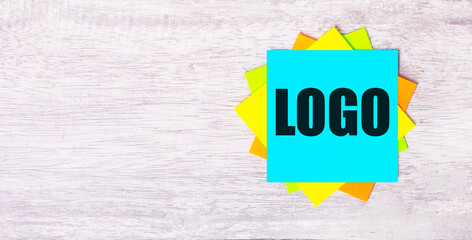 On a light gray wooden background, bright stickers with the text LOGO.