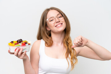 Young pretty woman holding a bowl of fruit isolated on white background proud and self-satisfied