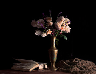 a bouquet of tea roses, with the addition of lavender, sprigs of barberry to the flower arrangement. still life in the classical style. bouquet of flowers in a vase on the table, with an open book