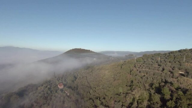 Tuscany hills sunset. Old castle on a mountain. Morning Fog