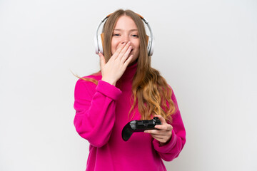 Young pretty woman playing with a video game controller isolated on white background happy and smiling covering mouth with hand