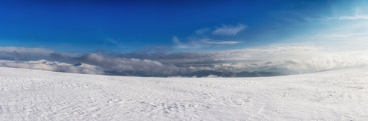 Fototapeta na wymiar Clouds over a snow-covered mountain range. Winter mountain landscape.