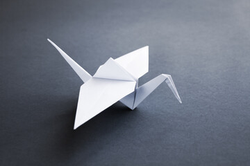 White paper crane origami isolated on a grey background