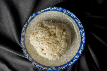Songkolo on a plate. Black fabric backdrop.