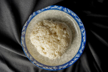 Songkolo on a plate. Black fabric backdrop.