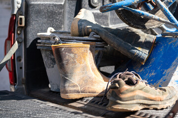 Dirty safety PPE and equipment of the construction worker which are placed on the truck of pick-up vehicle. Industrial working equipment object photo, selective focus. - obrazy, fototapety, plakaty