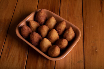 Por&ccedil;&atilde;o de coxinha sobre mesa de madeira