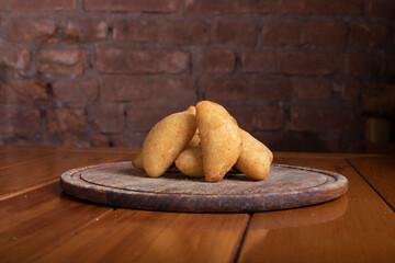 Por&ccedil;&atilde;o de risoles sobre mesa de madeira em tabua r&uacute;stica