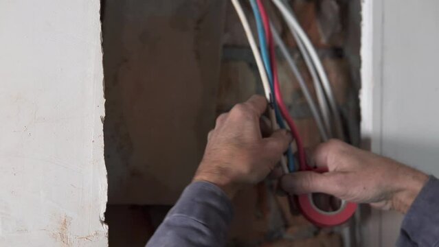 An electrician insulates wires in a switchboard.