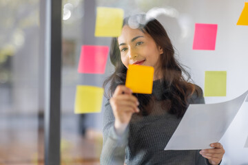 Business female employee with many conflicting priorities arranging sticky notes commenting and...