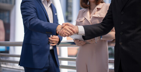 Handshake business partners at a meeting, focus on woman.