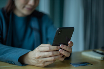 Senior asian woman using smartphone while sitting at home office.