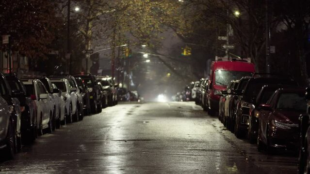 Empty street in residential district, rainy night. Heavy rain in the city. View of rows of cars parked along the road, no people. Dark night