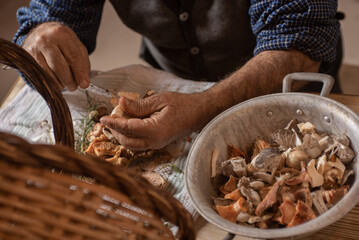 detail of old man's hands cleaning mushrooms with knife, basket with dirty and clean mushrooms cut in a sieve
