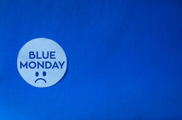 Fondo azul de papel con circulo blanco y blue monday representado con letras y una cara triste el...
