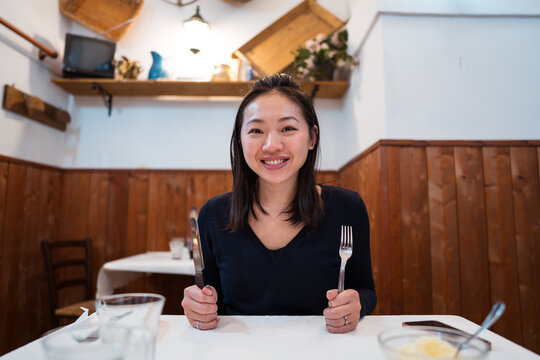 Cheerful Asian woman with silverware ready to eat