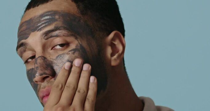 Positive man face mask. Relaxed man making natural cosmetic facial procedure