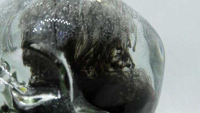 Black paint in a glass transparent skull swirls slowly	
