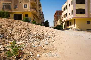 Hurghada, Egypt, Wasteland dune with garbage on dirt road leading to half abandoned residential...