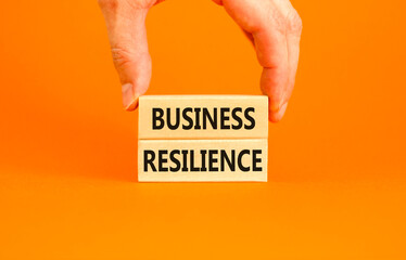 Business resilience symbol. Concept word Business resilience typed on wooden blocks. Beautiful orange table orange background. Businessman hand. Business and business resilience concept. Copy space.